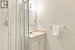 Shower enclosure with clear glass door, single vanity with integrated sink, light-toned countertop, vanity cabinet with dual doors, and wall-mounted mirror - 