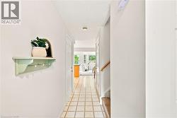 Tiled flooring, white interior walls, white paneled doors, wood handrail, recessed lighting - 