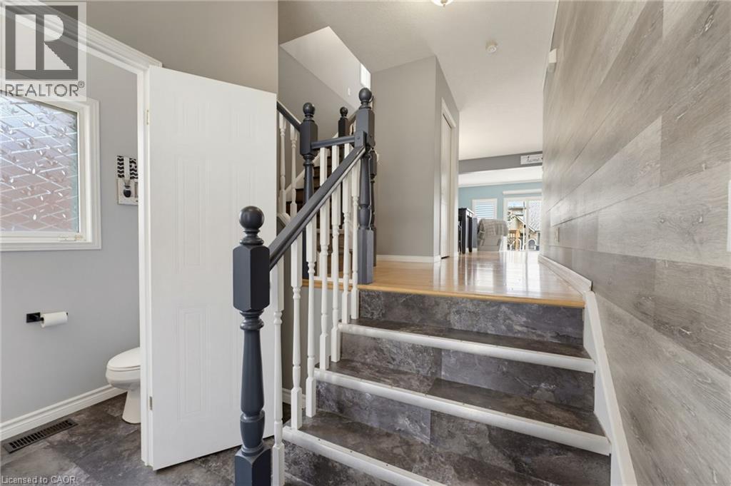 Staircase with dark-toned treads and balusters, light wood-finish flooring on the landing, and a paneled accent wall - 592 Little Dover Crescent, Waterloo, ON - Indoor Photo Showing Other Room