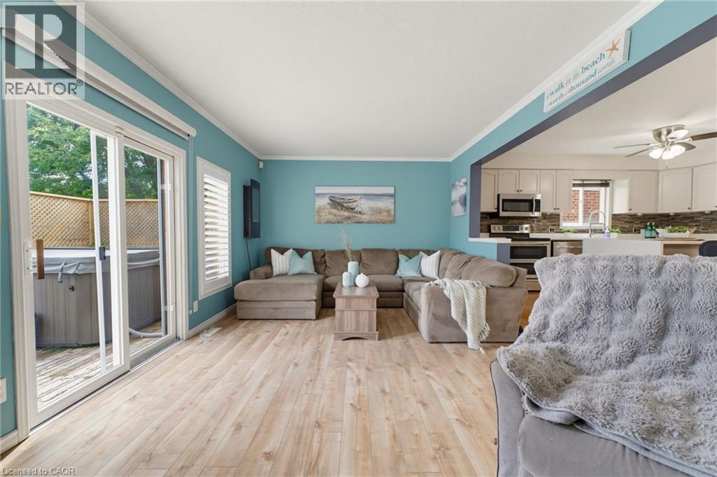 Wood-finish flooring throughout, sliding glass door to exterior, white plantation shutters, built-in kitchen cabinetry with stainless steel appliances - 592 Little Dover Crescent, Waterloo, ON - Indoor Photo Showing Living Room