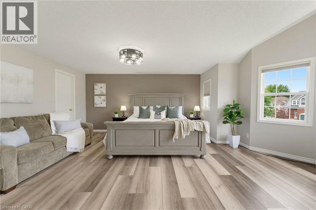 Spacious room featuring wood-finish flooring, vaulted ceiling, and a prominent window - 592 Little Dover Crescent, Waterloo, ON - Indoor Photo Showing Other Room