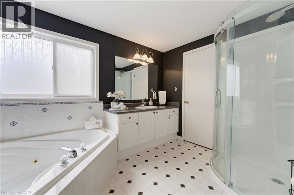 White soaking tub with chrome fixtures, complete with a tiled surround - 592 Little Dover Crescent, Waterloo, ON - Indoor Photo Showing Bathroom