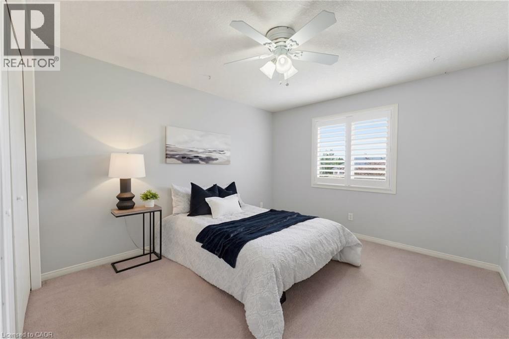 Angled ceiling line, ceiling fan with integrated lighting, window with plantation shutters, light-toned carpet, and a light-colored wall finish - 592 Little Dover Crescent, Waterloo, ON - Indoor Photo Showing Bedroom