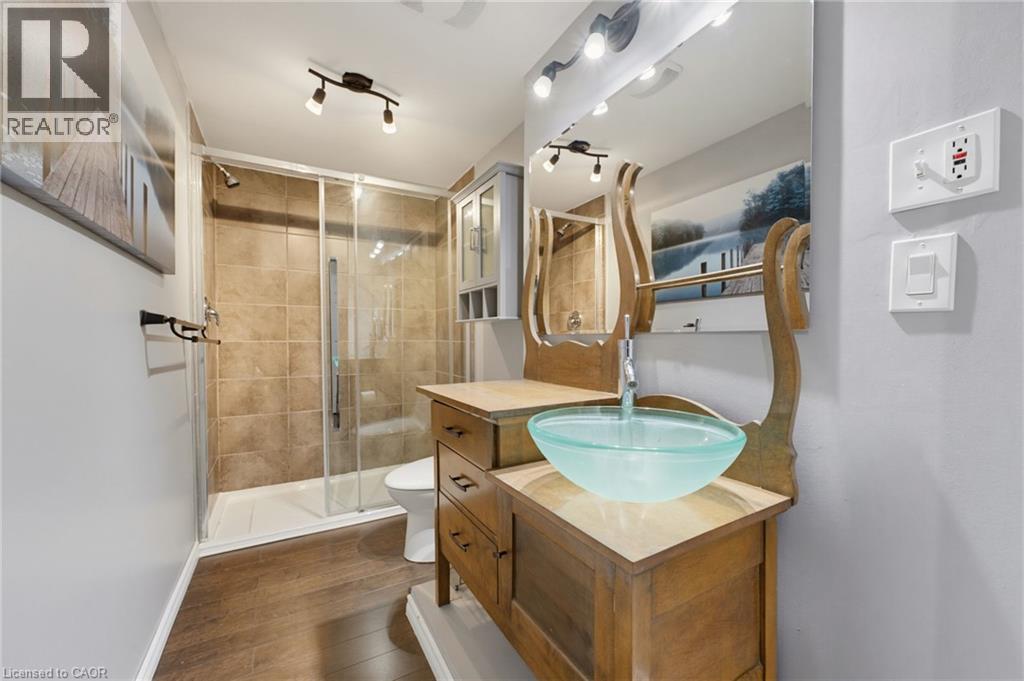 Wood-finish flooring, glass vessel sink, track lighting, tiled shower with glass enclosure, custom vanity - 592 Little Dover Crescent, Waterloo, ON - Indoor Photo Showing Bathroom