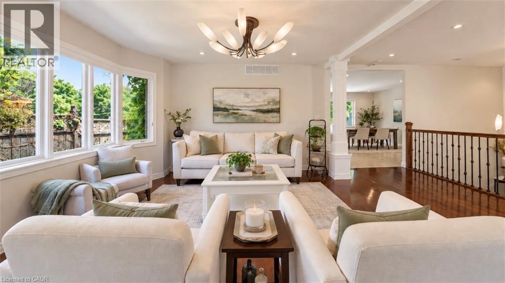 Open concept living area featuring expansive windows, wood-finish flooring, and a decorative ceiling light fixture - 56 Windrush Trail, Kitchener, ON