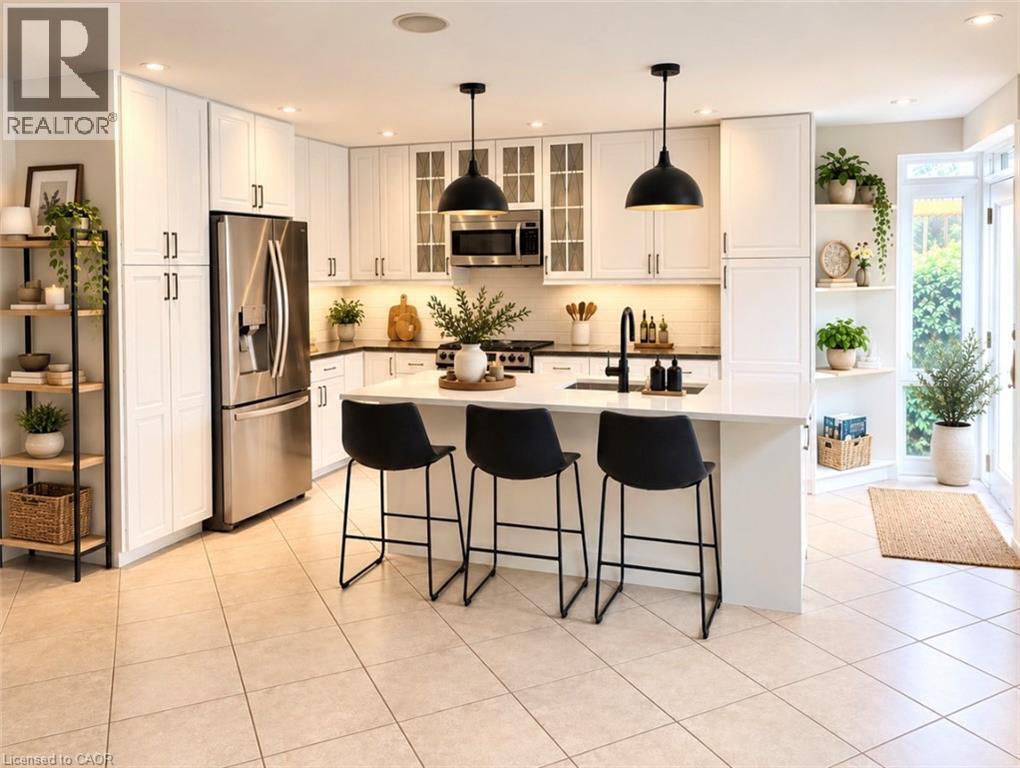 White cabinetry with black hardware, stainless steel appliances, a center island with pendant lighting, a built-in kitchen sink, and tiled flooring - 56 Windrush Trail, Kitchener, ON