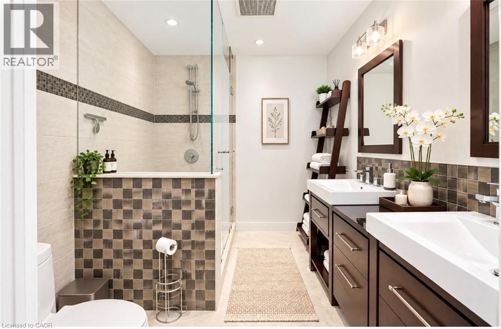 Dual vanity with vessel sinks, glass-enclosed shower, tiled half-wall, recessed lighting, and wall-mounted vanity lighting - 56 Windrush Trail, Kitchener, ON