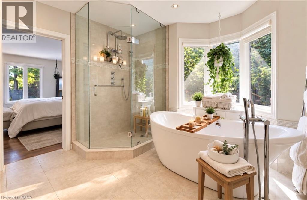 Freestanding soaking tub with floor-mounted faucet, glass-enclosed shower with multiple showerheads, recessed lighting, and tile flooring - 56 Windrush Trail, Kitchener, ON