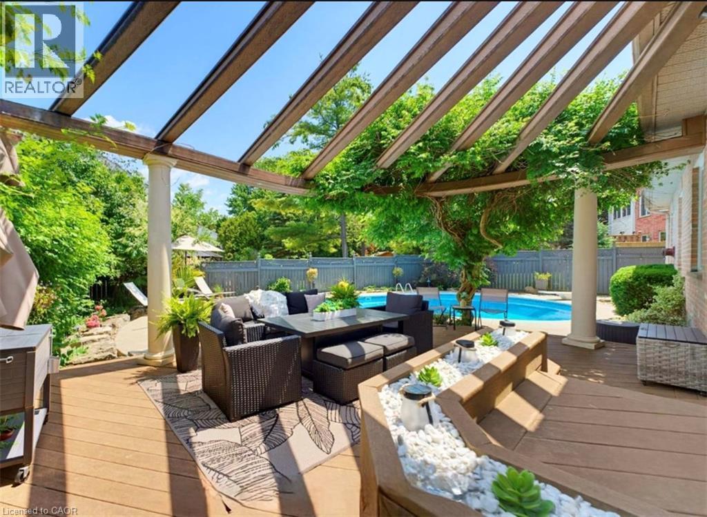 Expansive multi-level wood-finish deck with a pergola, column accents, built-in planters, and an in-ground swimming pool - 56 Windrush Trail, Kitchener, ON
