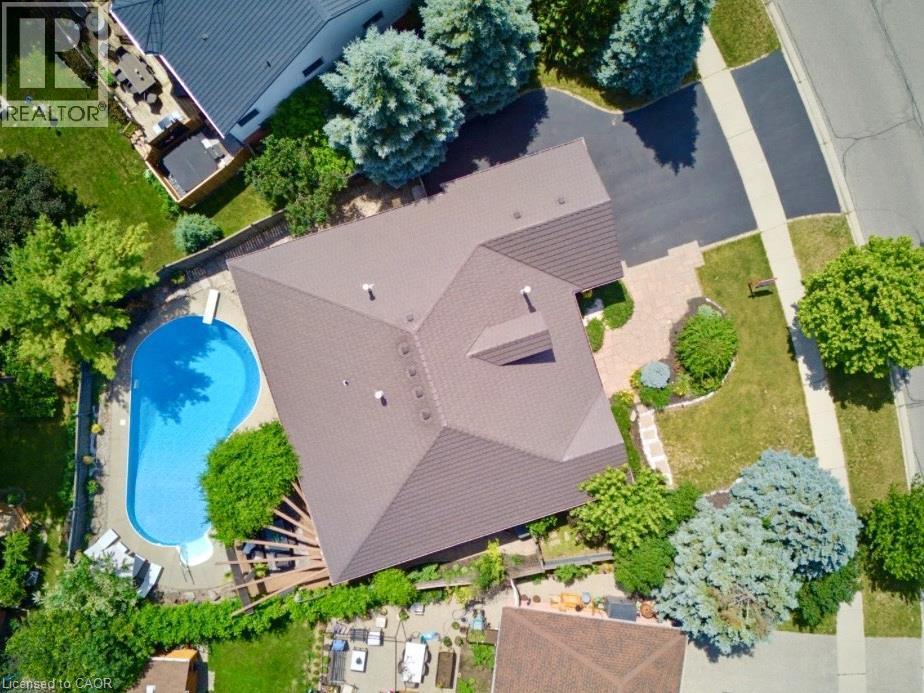 Outdoor pool with a diving board, paved driveway, mature trees, and landscaping - 56 Windrush Trail, Kitchener, ON