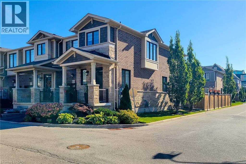 Brick exterior with stone accents, bay window, covered porch, decorative porch columns, and mature landscaping - 65 Waterview Lane, Grimsby, ON