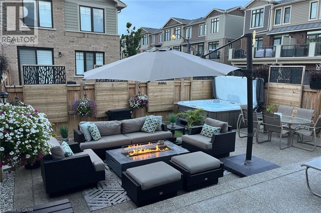 Paved patio featuring a built-in hot tub, fire pit, and privacy fencing - 65 Waterview Lane, Grimsby, ON