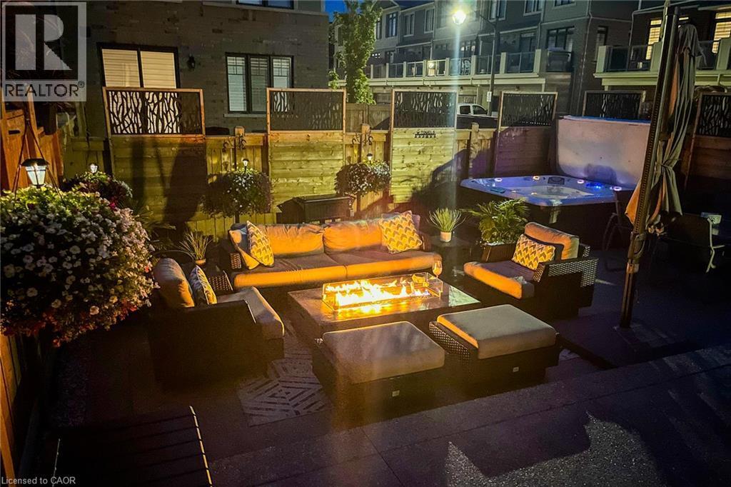 Outdoor patio featuring a built-in hot tub, privacy screens, and a fire pit - 65 Waterview Lane, Grimsby, ON