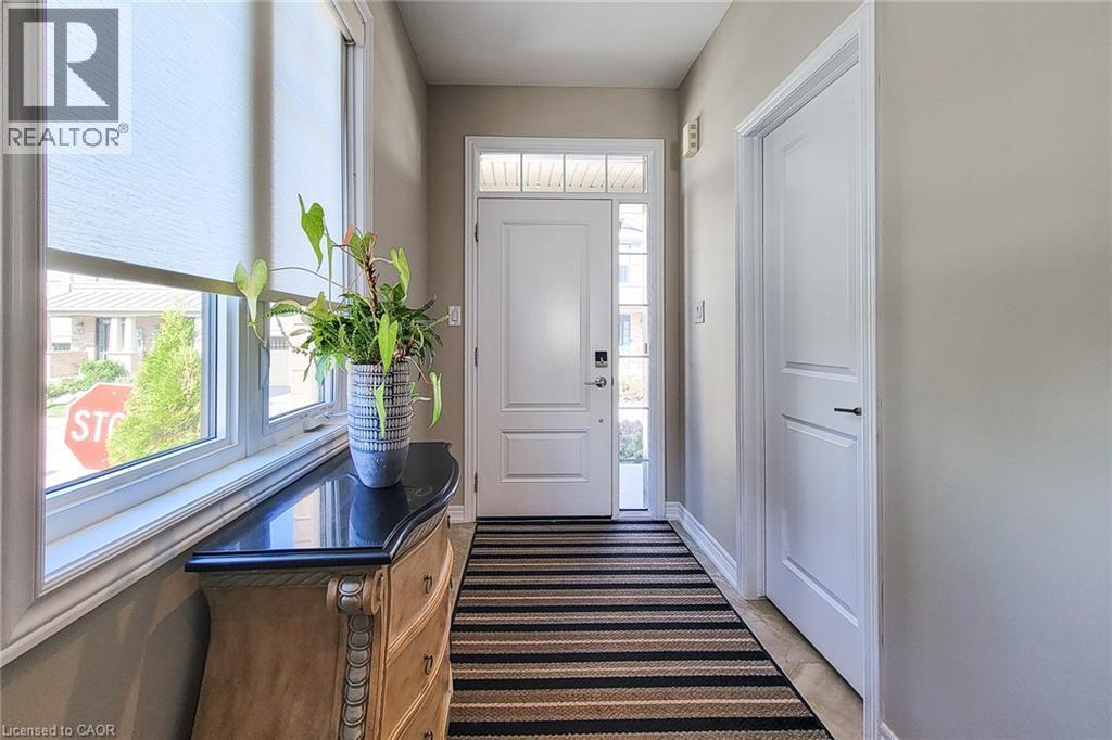 Entryway featuring a white paneled door with transom window, sidelight, and an integrated smart lock - 65 Waterview Lane, Grimsby, ON