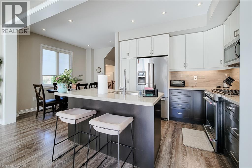 Kitchen featuring stainless steel appliances, a center island with seating, wood-finish flooring, recessed lighting, and ample cabinetry - 65 Waterview Lane, Grimsby, ON