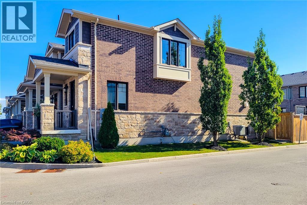 Brick and stone exterior with a covered porch, bay window, and manicured landscaping - 65 Waterview Lane, Grimsby, ON