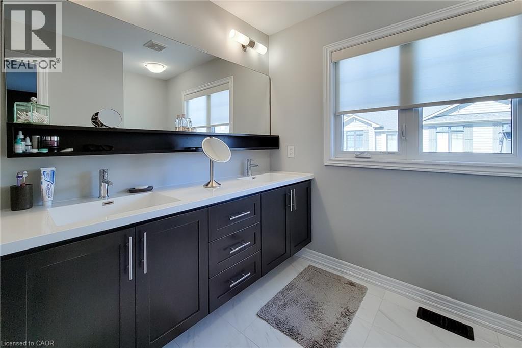 Double vanity with integrated rectangular sinks, modern faucets, and dark wood-finish cabinetry - 65 Waterview Lane, Grimsby, ON
