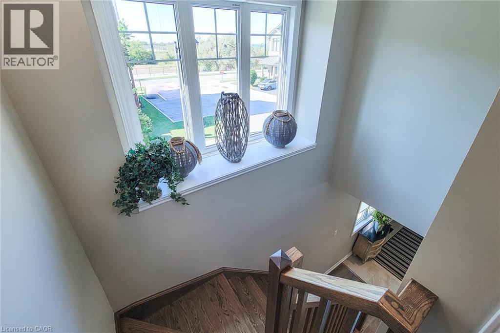 Staircase featuring wood-finish treads and risers, wood newel posts, and wood handrails - 65 Waterview Lane, Grimsby, ON