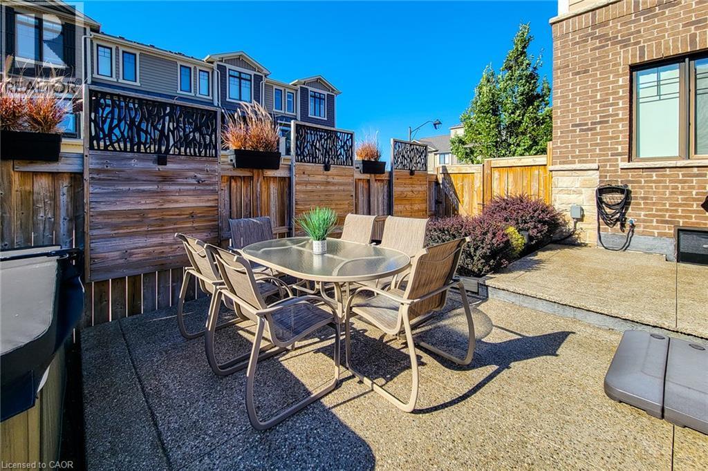 Concrete patio with surrounding wood fencing and decorative privacy screens - 65 Waterview Lane, Grimsby, ON