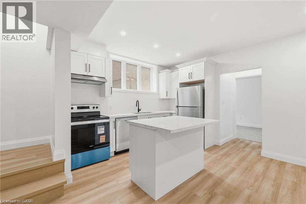 Contemporary kitchen featuring white cabinetry, stainless steel appliances, a center island with countertop, wood-finish flooring, and recessed lighting - 36 Elliott Street Unit# 1, Cambridge, ON
