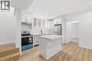 Contemporary kitchen featuring white cabinetry, stainless steel appliances, a center island with countertop, wood-finish flooring, and recessed lighting - 36 Elliott Street Unit# 1, Cambridge, ON 