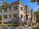 Modern multi-level exterior featuring gray brick and wood-look paneling, black-framed windows, integrated outdoor lighting, and stone retaining walls - 36 Elliott Street Unit# 1, Cambridge, ON 