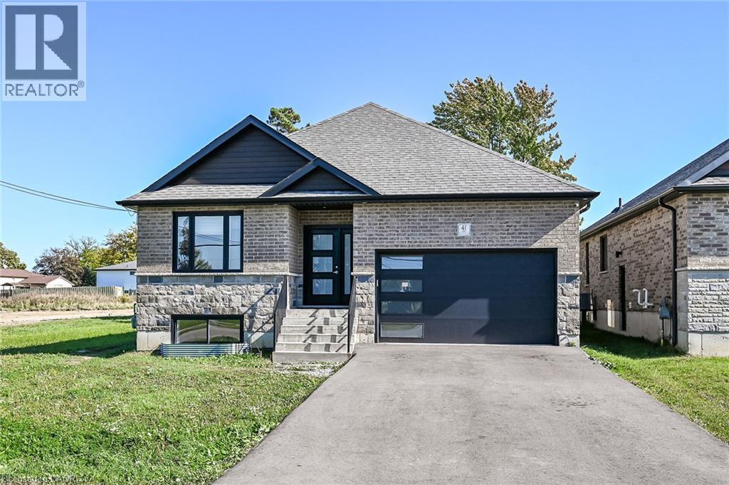 Contemporary exterior with a dark gray shingle roof, light brick siding, stone facade, and a modern garage door with frosted glass panels - 41 Eleanor Avenue, Hamilton, ON