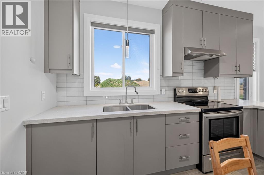 Gray cabinetry with modern hardware, light-toned countertops, subway tile backsplash, stainless steel range, and stainless steel range hood - 41 Eleanor Avenue, Hamilton, ON