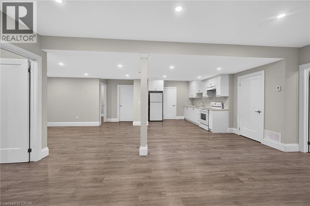 Open-concept living area featuring wood-finish flooring, recessed lighting, and a kitchen with white cabinetry - 41 Eleanor Avenue, Hamilton, ON