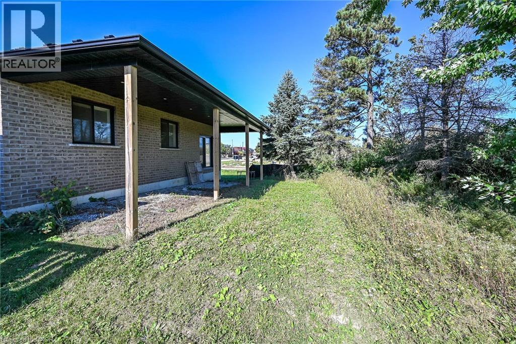 Covered rear patio extending along the brick exterior - 41 Eleanor Avenue, Hamilton, ON