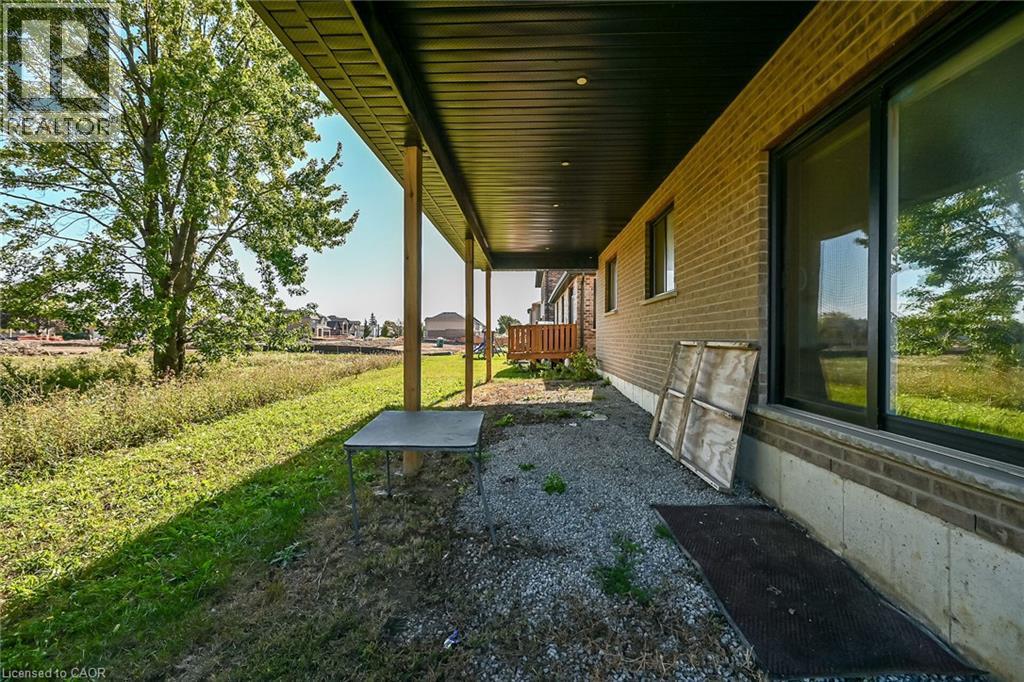 Brick exterior with multiple windows and a covered patio area featuring support columns - 41 Eleanor Avenue, Hamilton, ON