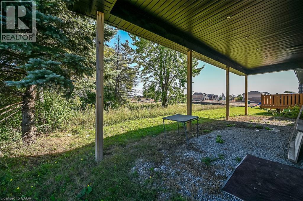 Covered outdoor patio with exposed wood support columns, gravel patio surface, and a slatted wood railing - 41 Eleanor Avenue, Hamilton, ON