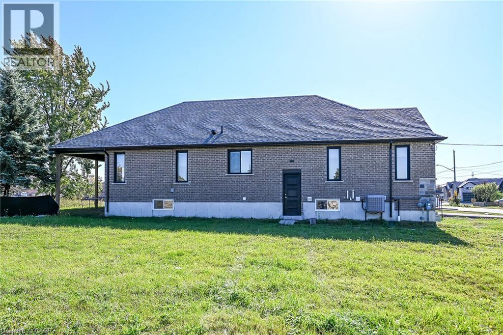 Brick exterior with a dark shingle roof, black-framed windows, and an outdoor covered area - 41 Eleanor Avenue, Hamilton, ON