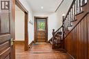 Foyer featuring wood-finish flooring, a traditional wood staircase with balusters, wood paneling, a wood entry door with glass upper portion, and wood trim - 245 Lowther Street S, Cambridge, ON 