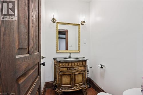 Powder room featuring a detailed wood-finish vanity with a dark countertop and integrated sink - 245 Lowther Street S, Cambridge, ON 