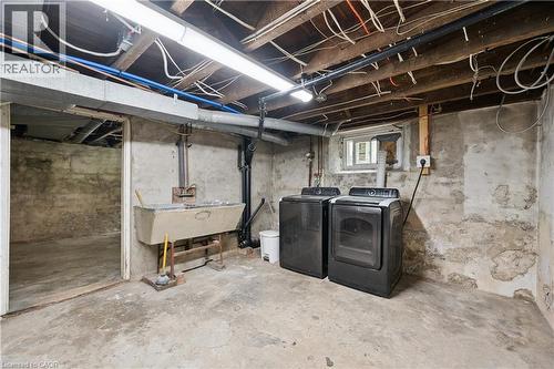 Basement utility area featuring a concrete floor, exposed wood ceiling joists, and a utility sink - 245 Lowther Street S, Cambridge, ON 