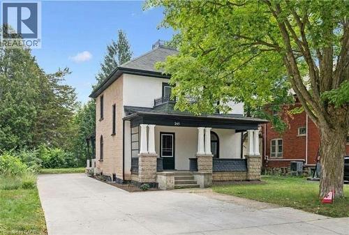 Two-story residence featuring a covered front porch with substantial columns, a paved driveway, and a stone-clad foundation - 245 Lowther Street S, Cambridge, ON 