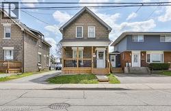 Stone exterior with a gabled roof, front porch with wood railings, and a gravel driveway -