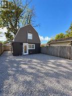 Gambrel-style exterior with gray siding, white trim windows, and a glass-paneled entry door -