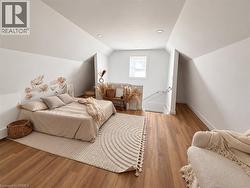Sloped ceilings, recessed lighting, wood-finish flooring, white walls, and a window -