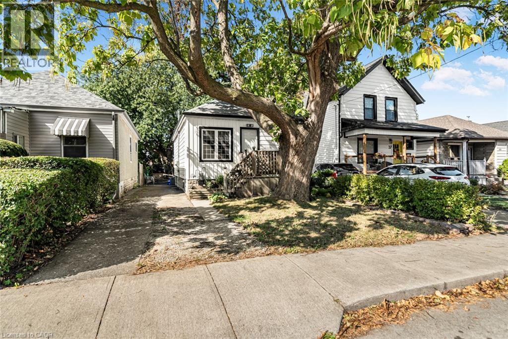 White siding exterior with black trim windows - 29 Wexford Avenue N, Hamilton, ON