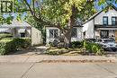 White exterior with black trim, concrete sidewalk, mature tree, and a paved driveway - 29 Wexford Avenue N, Hamilton, ON 