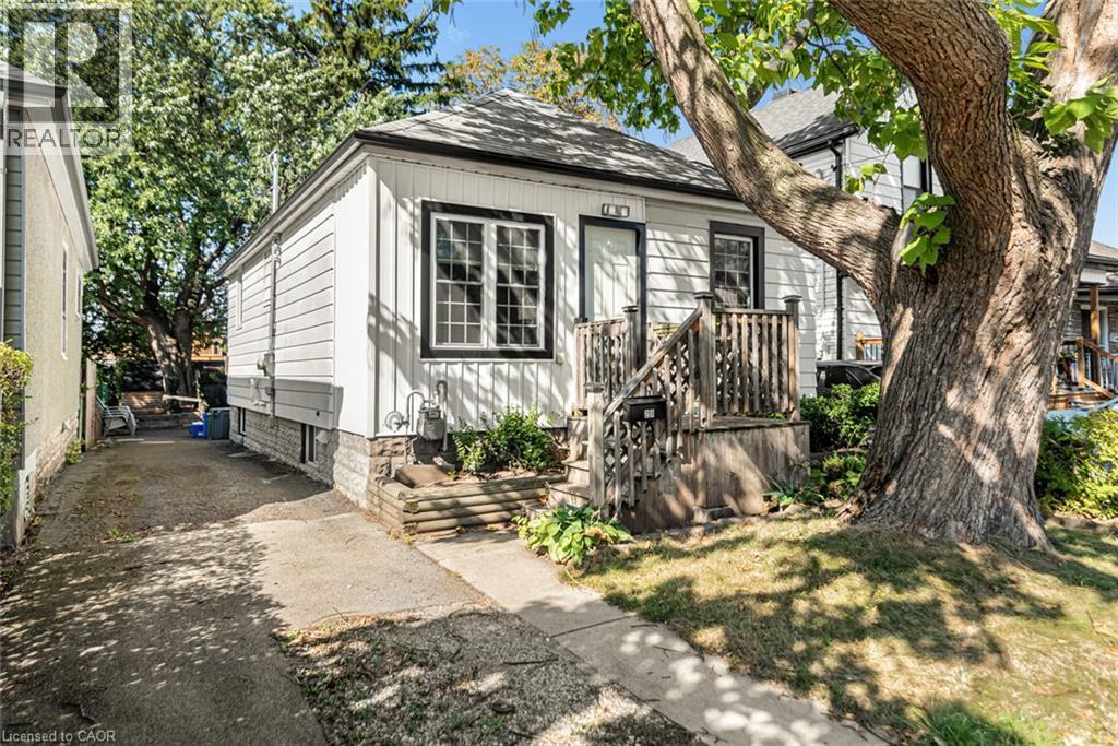 White horizontal siding exterior with black trim windows, a covered front porch, and a concrete driveway - 29 Wexford Avenue N, Hamilton, ON