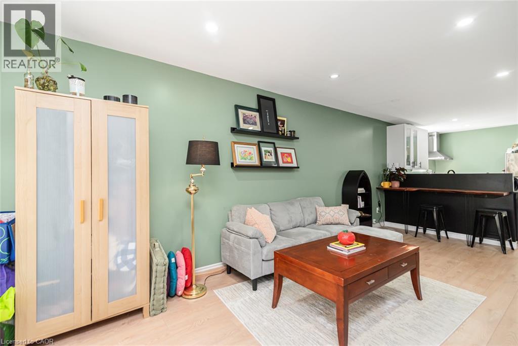 Recessed lighting, wood-finish flooring, and a kitchen featuring white cabinetry and a stainless steel range hood - 29 Wexford Avenue N, Hamilton, ON