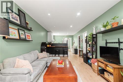 Recessed lighting throughout, wood-finish flooring, two large floating shelves, built-in breakfast bar, and white upper cabinetry - 29 Wexford Avenue N, Hamilton, ON 