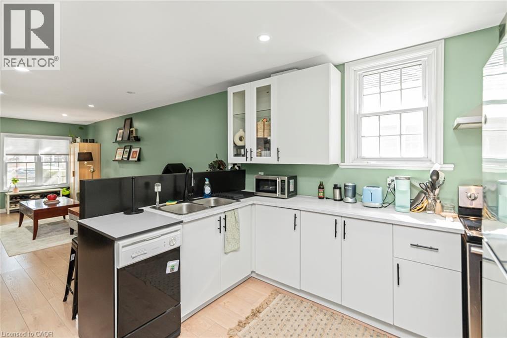 Kitchen featuring white cabinetry, a double basin sink, and stainless steel appliances - 29 Wexford Avenue N, Hamilton, ON