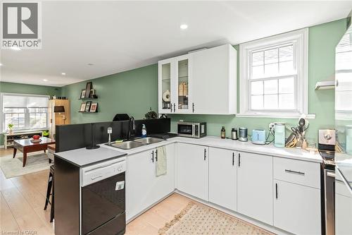 Kitchen featuring white cabinetry, a double basin sink, and stainless steel appliances - 29 Wexford Avenue N, Hamilton, ON 
