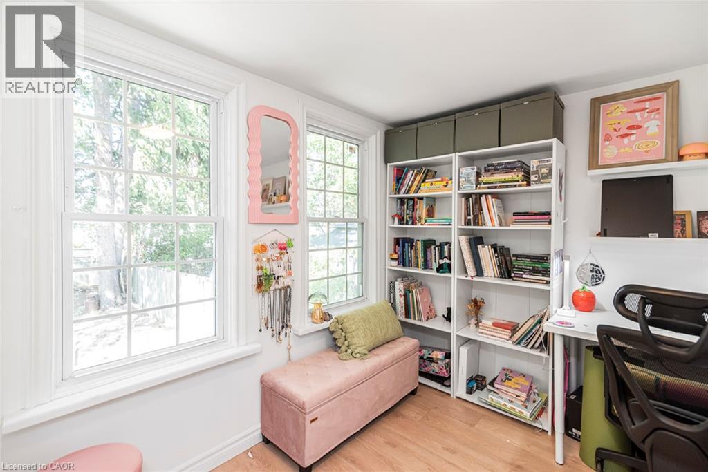 Two multi-pane windows with white trim, light wood-finish flooring, white built-in shelving, and white wall-mounted shelving - 29 Wexford Avenue N, Hamilton, ON