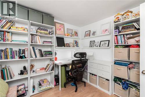 Built-in shelving units with ample storage, integrated desk area, and wood-finish flooring - 29 Wexford Avenue N, Hamilton, ON 