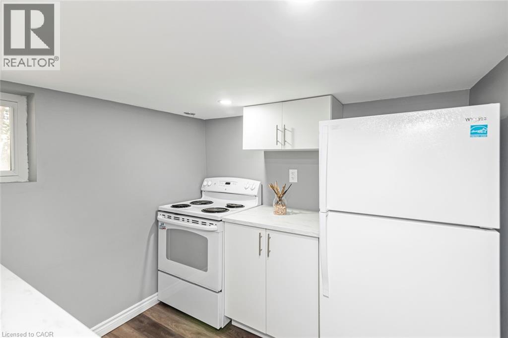 White appliances, white cabinetry, light countertops, and wood-finish flooring - 29 Wexford Avenue N, Hamilton, ON